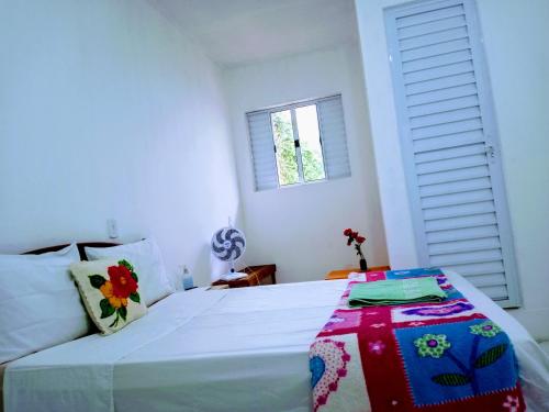 a bedroom with a large white bed with a window at Minha casa pousada in Botucatu