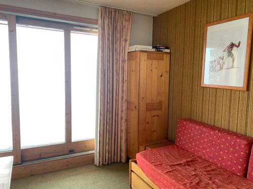 a room with a red couch and two large windows at Valmorel Studio Skis aux pieds in Valmorel