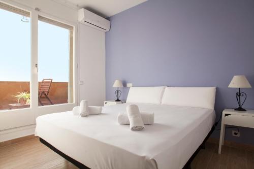Cama blanca en habitación con ventana grande en Stay U-nique Apartments Marina III, en Barcelona