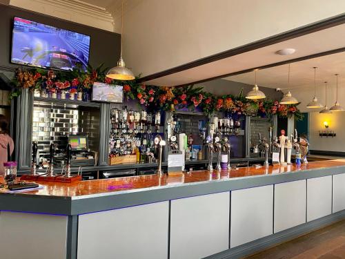 a bar with a counter with flowers and a tv at The New Brighton Hotel in New Brighton