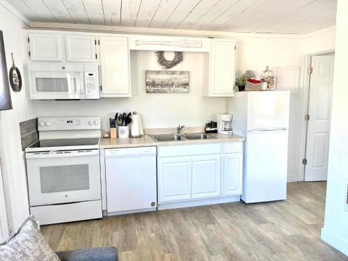 una cocina con electrodomésticos blancos y armarios blancos en Arena del Mar en Grayland