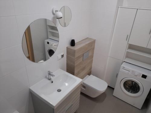 a white bathroom with a sink and a washing machine at Apartament Słowackiego Września in Września