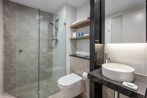 a bathroom with a toilet and a sink and a shower at Meriton Suites Sussex Street, Sydney in Sydney