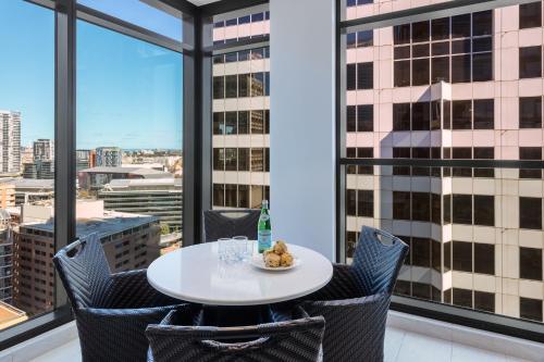 a table and chairs in a room with large windows at Meriton Suites Sussex Street, Sydney in Sydney