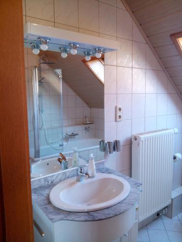 a bathroom with a sink and a mirror and a tub at Ferienwohnung "LEONORE" Eppendorf in Eppendorf