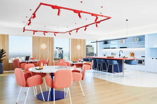 a kitchen with orange chairs and tables in a room at Scape Living at Franklin in Melbourne