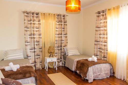 a bedroom with two beds and a chandelier at Casa do Prendinha by Horizon View Madeira in Ponta do Pargo