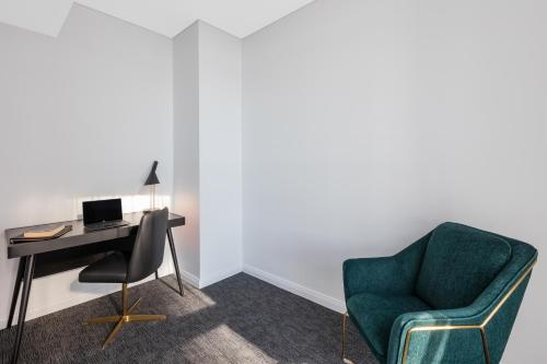 a room with a desk and a chair and a computer at Meriton Suites Sussex Street, Sydney in Sydney