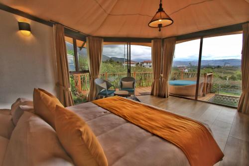 - une chambre avec un grand lit et une grande fenêtre dans l'établissement GENKI LUXURY GLAMPING, à Villa de Leyva