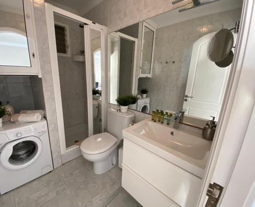a bathroom with a toilet sink and a washing machine at Doñana12 by SunHousesCanarias in Patalavaca
