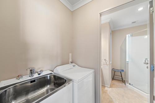 a bathroom with a sink and a washing machine at Lakeside Vistas Magic - Rainbow Point Home in Taupo