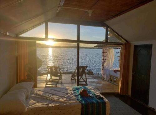 a bedroom with a view of the ocean from a balcony at Uros Tikarani hotel in Puno