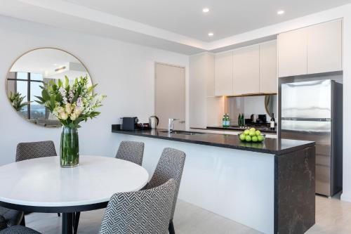 a kitchen with a table with a vase of flowers at Meriton Suites Sussex Street, Sydney in Sydney