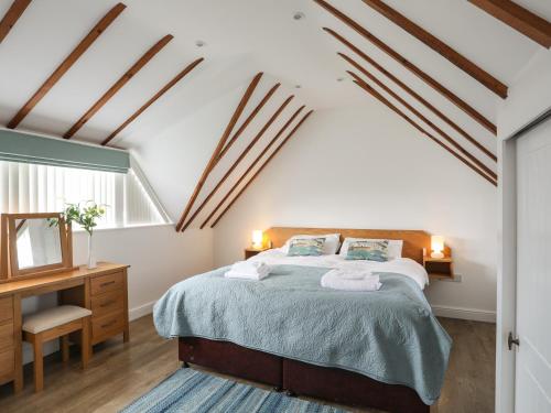 a bedroom with a bed and a desk and a window at Tyn Towyn - Ty Coch in Trearddur