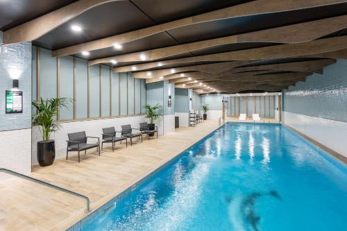 a swimming pool in a hotel with chairs and tables at Meriton Suites Sussex Street, Sydney in Sydney