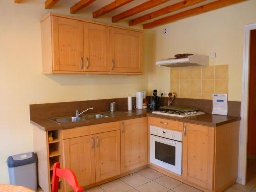 a kitchen with wooden cabinets and a sink and a stove at Maison ancienne entièrement rénovée pour 5 personnes in Bény-sur-Mer