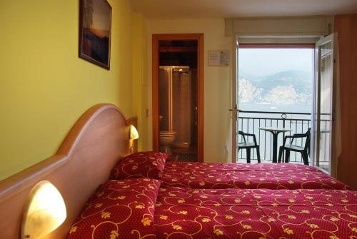 ブレンゾーネにあるHotel Residence Panoramicaのベッドとバルコニー付きのホテルルーム