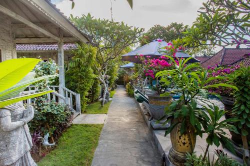 a garden with potted plants and an umbrella at 221 Garden Cottages in Nusa Lembongan