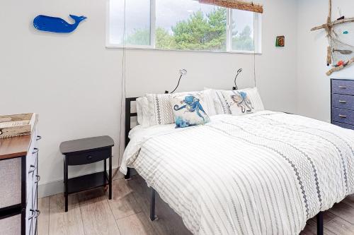 a bedroom with a bed with white sheets and a window at Driftwood Duet in Bandon