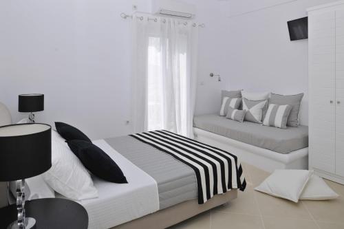 a white bedroom with two beds and a window at Romantica Suites in Naousa