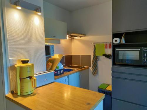 a small kitchen with a wooden table and a microwave at studio à l'océan au dessus des pins (plage & commerces à pied) in Seignosse