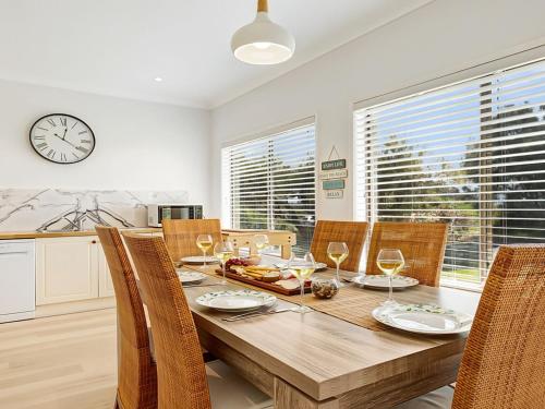 a dining room with a table and chairs and a clock at Windspray in Culburra Beach