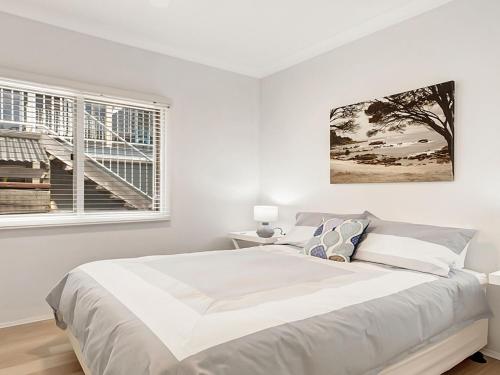 a white bedroom with a large bed and a window at Windspray in Culburra Beach