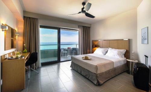 a bedroom with a bed and a view of the ocean at Ostria Sea Side Hotel in Hanioti