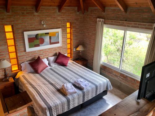 a bedroom with a bed and a large window at Cabañas Del Rio in Mina Clavero