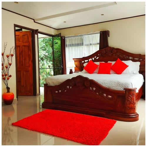 a bedroom with a large wooden bed with red pillows at Dreams Lodge in Monteverde Costa Rica