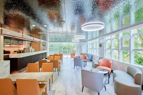 un restaurante con sillas naranjas, mesas y ventanas en Uni-Resort Ku-Kuan, en Heping