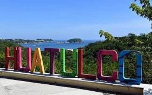 a sign for the hollywood sign with the ocean in the background at Departamento Anel en Huatulco in Santa Cruz Huatulco