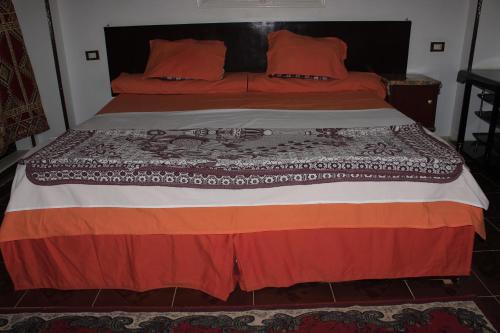 a bed with orange and orange pillows on it at Nuba Dool in Aswan