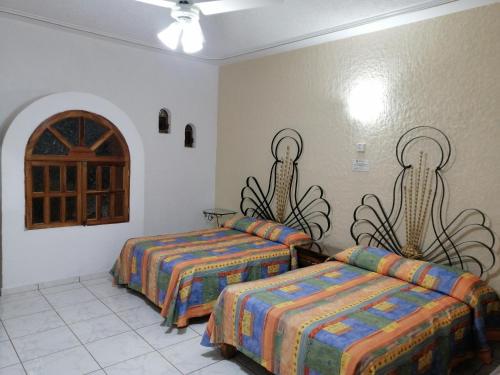 une chambre d'hôtel avec deux lits et une fenêtre dans l'établissement Hotel Providencia, à Talpa de Allende