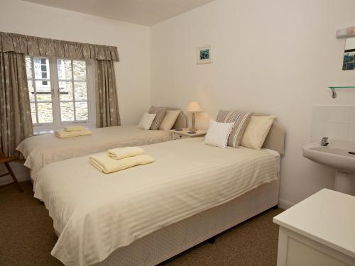 two beds in a white room with a sink at 3 Moult Farm Cottage in Salcombe