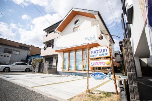 un bâtiment blanc avec un panneau devant lui dans l'établissement Katsuo Guest House, à Kōchi