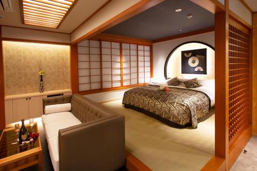 a bedroom with a bed and a couch in it at HOTEL MYTH-CLUB -ホテル マイス クラブ- Adult Only in Kyoto