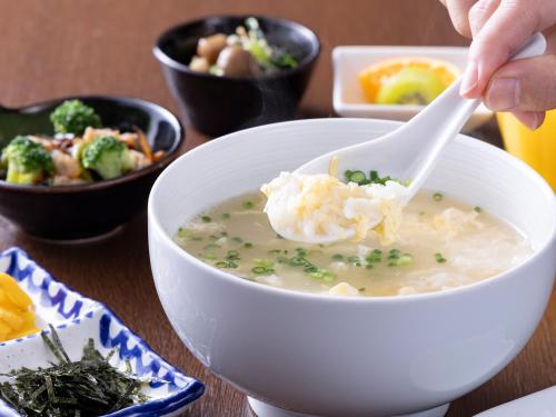 a person eating a bowl of soup with a spoon at Hotel Wing International Shimonoseki in Shimonoseki