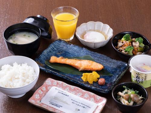 a table topped with plates of food and bowls of rice at Hotel Wing International Shimonoseki in Shimonoseki