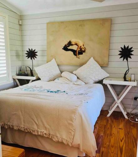 a bedroom with a bed with a painting on the wall at Exquisite chalet on private nature reserve in Wolseley