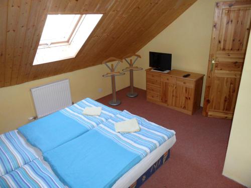 ein Schlafzimmer mit einem blauen Bett und einem TV in der Unterkunft Penzion Skalíček in Königseck