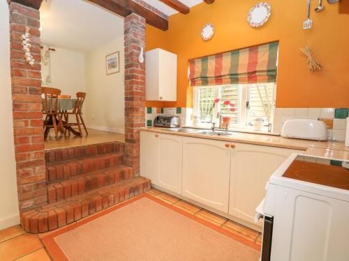 a kitchen with orange walls and a brick wall at Sleepeezy in Kettlestone