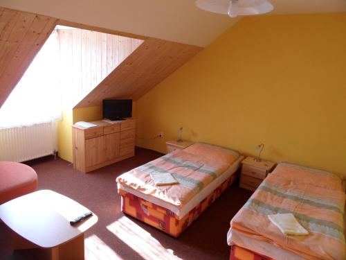 a attic bedroom with two beds and a tv at Penzion Skalíček in Kunžak