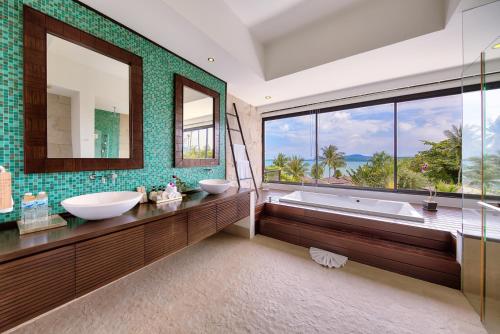 La salle de bains est pourvue de 2 lavabos, d'une baignoire et d'une grande fenêtre. dans l'établissement Dhevatara Residence Sea View Villas, à Bophut 
