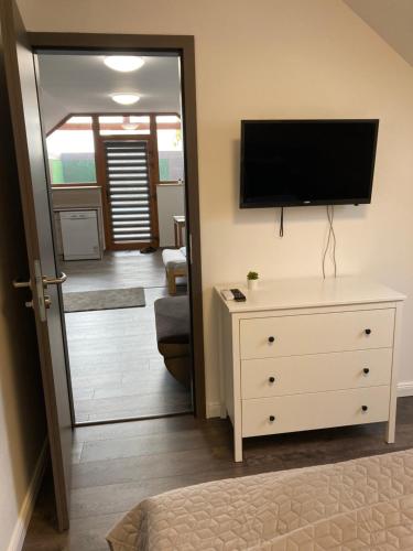 a living room with a television and a dresser with a tv on the wall at Platán Panzió in Csongrád