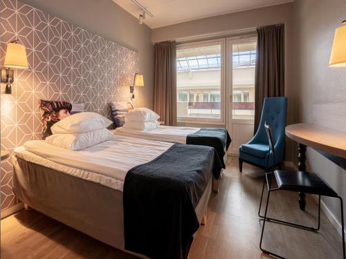 a hotel room with two beds and a blue chair at Original Sokos Hotel Vaakuna Mikkeli in Mikkeli