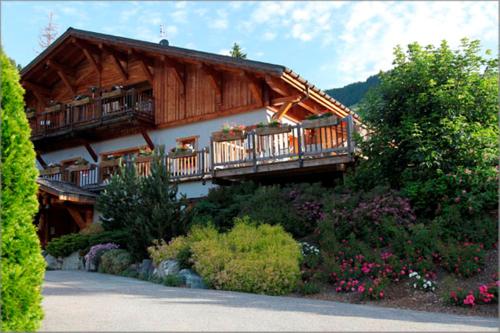 a large wooden house with a balcony and flowers at Hôtel La Ferme du Chozal, Chalet de tradition in Hauteluce