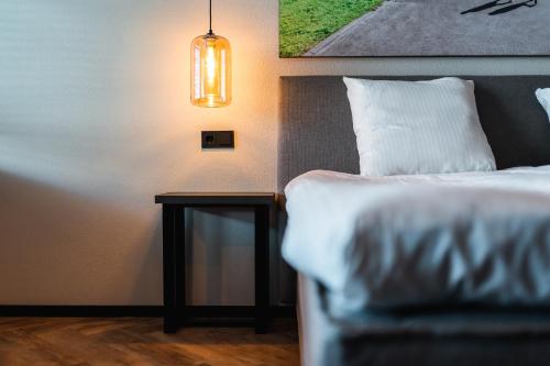 a bedroom with a bed and a table with a lamp at Onderwijshotel De Rooi Pannen Eindhoven in Eindhoven