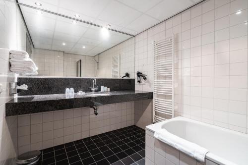 a white bathroom with a tub and a sink at Onderwijshotel De Rooi Pannen Eindhoven in Eindhoven