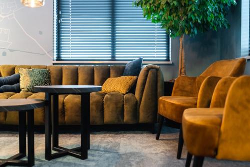 a living room with a couch and two tables and chairs at Onderwijshotel De Rooi Pannen Eindhoven in Eindhoven